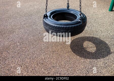 un pneu en caoutchouc en plastique noir se balance sur un parc de jeu pour enfants Banque D'Images