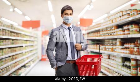 Jeune homme dans des vêtements formels shopping dans un supermarché et portant un masque de protection Banque D'Images