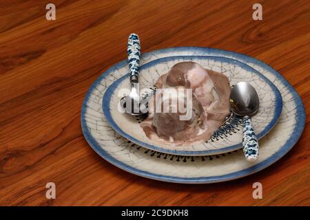 boules de glace colorées et deux cuillères servies sur des assiettes élégantes, en gros plan. Banque D'Images