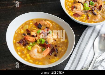 Maïs doux, bacon poivré et chaudrée de crevettes : bols de chaudrée de fruits de mer avec légumes et bacon garni d'oignons verts Banque D'Images