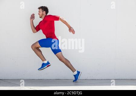 Homme de course entraînement de coureur faire des courses de ville en plein air sprint le long de fond de mur. Vie urbaine saine et active. Athlète masculin faisant sprint hiit Banque D'Images