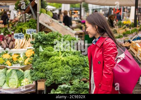 Jeune femme asiatique achetant des légumes frais sur le marché alimentaire des agriculteurs avec un sac à provisions. Une jeune fille de race blanche chinoise qui marche à l'extérieur. Banque D'Images