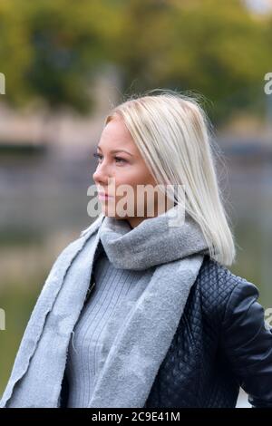 Jeune belle femme blonde pensant contre la vue floue de la rivière Banque D'Images