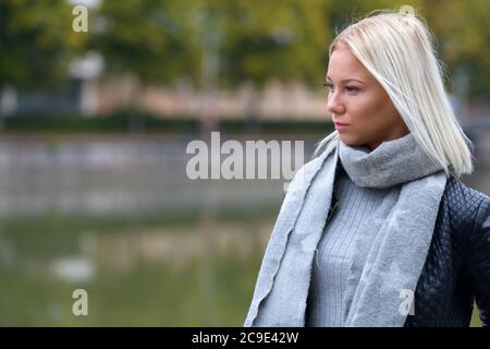 Jeune belle femme blonde pensant dans le parc le long de la rivière Banque D'Images