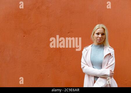 Jeune belle femme blonde contre le mur orange à l'extérieur Banque D'Images