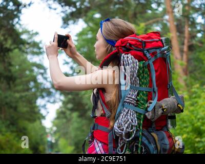 Vue arrière d'une randonneur dans la forêt fait une photo avec son téléphone portable. Concept d'écotourisme. Banque D'Images