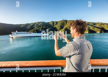 Voyage de croisière homme touriste prenant la photo de téléphone de bateau de ferry croisière sur la mer. Photos de tourisme pendant les vacances de passage de l'île de Nouvelle-Zélande à Marlborough Banque D'Images