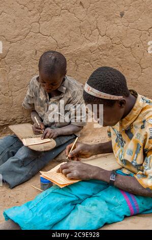 Les garçons Dogon écrivent sur des tablettes en bois dans une école du Coran dans le village de Dogon de Niogono dans la région de Bandiagara, pays Dogon, Mali, Afrique de l'Ouest. Banque D'Images