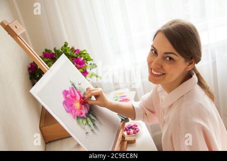 Vue de dessus de jeune caucasien jolie fille artiste peint esquisse de fleur rose Banque D'Images