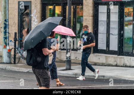 Montréal, CA - 30 juillet 2020 : personnes sur l'avenue Mont-Royal tenant des parasols sous la pluie et la tempête Banque D'Images