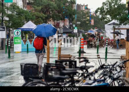 Montréal, CA - 30 juillet 2020 : femme sur l'avenue Mont-Royal tenant un parapluie sous la pluie et la tempête Banque D'Images