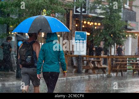 Montréal, CA - 30 juillet 2020 : personnes sur l'avenue Mont-Royal tenant un parapluie sous la pluie et la tempête Banque D'Images