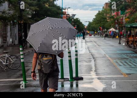 Montréal, CA - 30 juillet 2020 : un homme sur l'avenue Mont-Royal tenant un parapluie sous la pluie et la tempête Banque D'Images