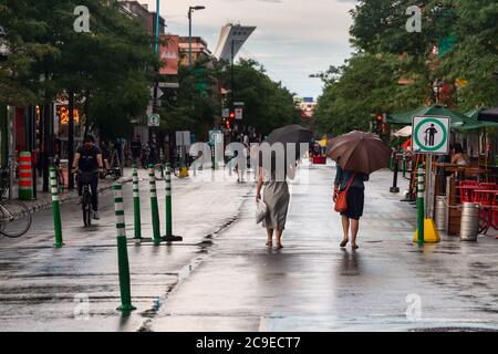 Montréal, CA - 30 juillet 2020 : personnes sur l'avenue Mont-Royal tenant des parasols sous la pluie et la tempête Banque D'Images