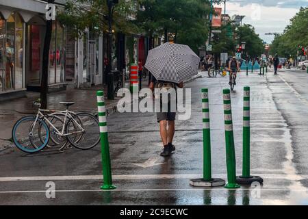 Montréal, CA - 30 juillet 2020 : un homme sur l'avenue Mont-Royal tenant un parapluie sous la pluie et la tempête Banque D'Images