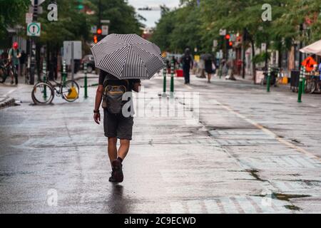 Montréal, CA - 30 juillet 2020 : un homme sur l'avenue Mont-Royal tenant un parapluie sous la pluie et la tempête Banque D'Images