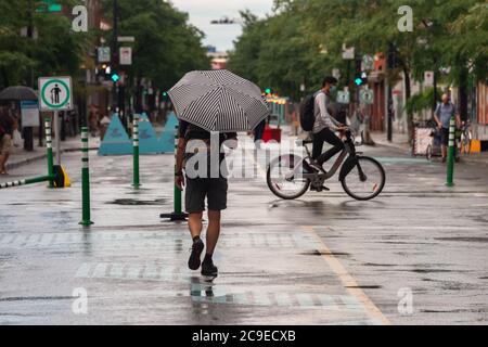 Montréal, CA - 30 juillet 2020 : un homme sur l'avenue Mont-Royal tenant un parapluie sous la pluie et la tempête Banque D'Images