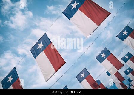 Un groupe de drapeaux texans accrochés au ciel bleu et aux nuages blancs. Banque D'Images