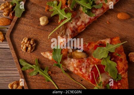 Flat Lay image de gros plan du fromage végétarien et de la pizza de tomate décorée de feuilles d'arugula fraîches et de tranches d'œufs grillées. Il est servi sur du bois Banque D'Images