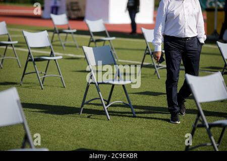 Se place l'un à côté de l'autre pour maintenir la distance sociale pendant l'épidémie de Covid-19 lors d'un événement en plein air sur le gazon d'un stade. Banque D'Images