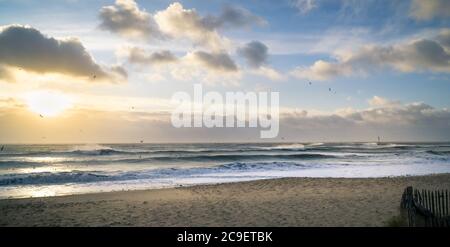 Lever de soleil au-dessus de la mer pendant une tempête. Des nuages spectaculaires . Les rayons du soleil illuminent un phare et les vagues. Vue panoramique Banque D'Images