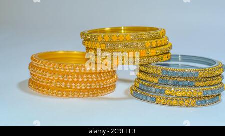 Bracelets en verre et métal bleus, dorés et jaunes sur fond blanc. Banque D'Images