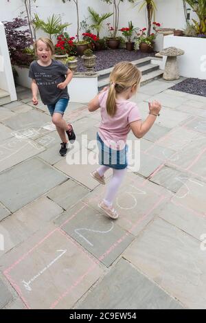 Enfants jouant au jeu traditionnel de hopscotch. Banque D'Images