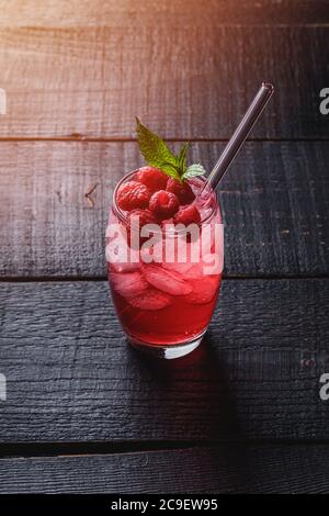 Glace fraîche boisson froide jus de baies à la menthe, limonade d'été à la framboise en verre avec pailles sur fond de bois foncé, vue en angle Banque D'Images