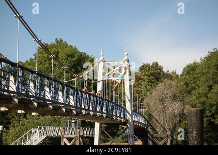 Garçons sautant de la passerelle Teddington Lock vers la Tamise, Teddington, Angleterre, Royaume-Uni Banque D'Images