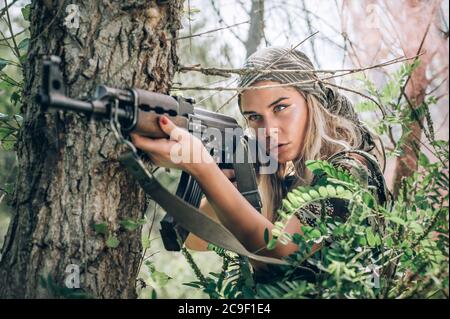 Belle et attrayante femme soldat de tir avec fusil mitrailleuse dans la forêt. Femme armée nature entraînement militaire de combat en plein air. fata Femme Banque D'Images