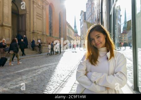 Bonne jeune belle femme touristique asiatique souriante aux bras croisés dans les rues de Suède Banque D'Images