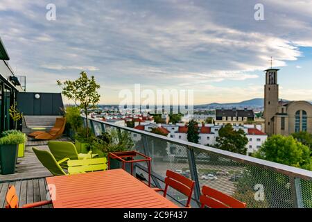 Mobilier d'extérieur vert et orange sur un toit-terrasse avec un ciel nuageux au-dessus et une église à droite Banque D'Images