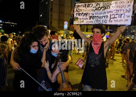 Jérusalem, ISRAËL 31 juillet 2020: Un manifestant tient une pancarte déplorant la destruction de la démocratie tandis que d'autres jouent des bourreurs comme environ 2000 personnes rassemblées pour une manifestation contre le Premier ministre Benjamin Netanyahu devant sa résidence officielle le 30 juillet 2020 à Jérusalem, Israël. Les Israéliens sont descendus dans la rue dans des manifestations presque quotidiennes pour appeler à la démission de Netanyahou suite à ses accusations de corruption et à ce qu'ils appellent un assaut contre la démocratie. Crédit : Eddie Gerald/Alay Live News Banque D'Images