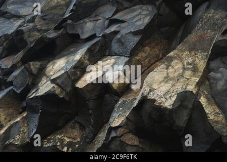Gros plan d'une formation de roche jaune et noire à la base d'une falaise. Détails et texture nets sur l'ensemble. Banque D'Images