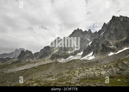 En regardant à travers les pics rocheux et tranchants d'une chaîne de montagnes. Gris, ciel nuageux et taches de neige entre les rochers. Banque D'Images