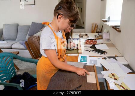 Garçon avec implant cochléaire apprenant à fabriquer des plaques lino linocut tout en imprimant dans un atelier d'art à Carmarthenshire Wales UK KATHY DEWITT Banque D'Images