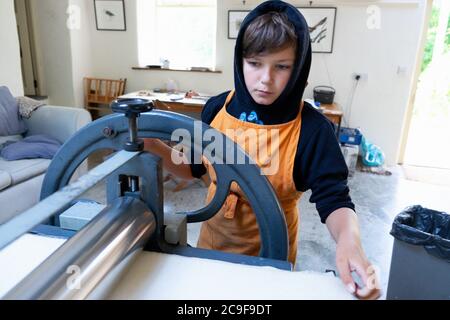 Garçon apprenant linocut lino cut printmaking dans un atelier de classe d'art travaillant sur Littlejohn gravure presse au pays de Galles Royaume-Uni Grande-Bretagne KATHY DEWITT Banque D'Images