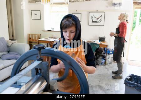 Garçon apprenant la gravure de linocut avec une femme artiste en atelier de classe d'art travaillant sur une presse de gravure à Carmarthenshire Wales UK KATHY DEWITT Banque D'Images