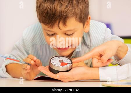 Garçon avec le trouble du spectre de l'autisme pendant la thérapie ABA regarder la minuterie de leçon dans les mains des enseignants comprendre le concept de temps Banque D'Images