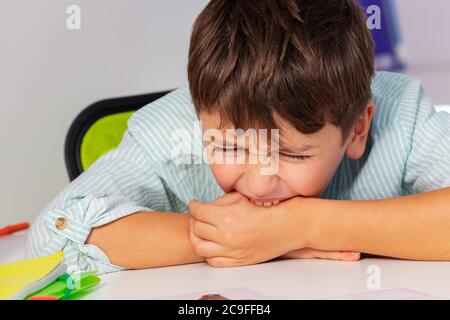 Garçon avec le trouble du spectre de l'autisme mordant la main et comportement d'expression négative, portrait de près Banque D'Images