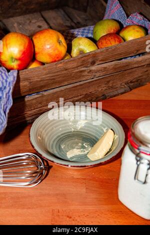 Ustensiles de cuisine, boîte en bois de pommes mûres, casserole, sucre dans un pot et beurre Banque D'Images