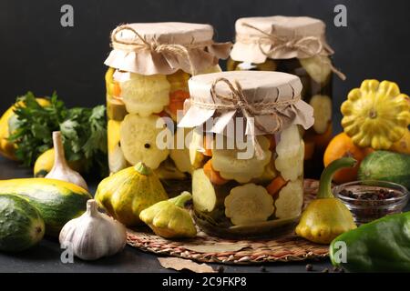 Trois bocaux avec des pâtisseries marinées, des concombres et des courgettes sur fond gris foncé avec des ingrédients frais, format horizontal Banque D'Images