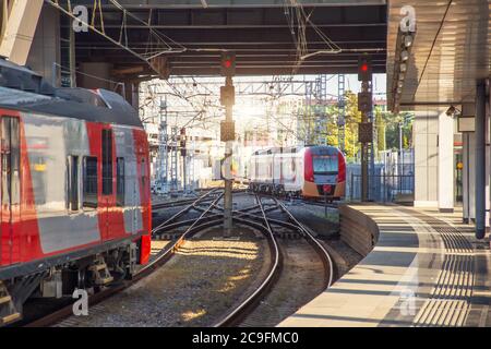 Le train express de banlieue quitte la gare, plate-forme vide. Un autre train attend les passagers Banque D'Images