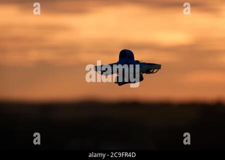 Race Copter également drone vole contre un ciel orange vif du soir. Le motif principal est presque représenté comme une silhouette. Allemagne. Banque D'Images