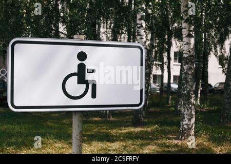 Panneau de stationnement pour personnes handicapées avec bâtiment résidentiel et bouleaux en arrière-plan Banque D'Images