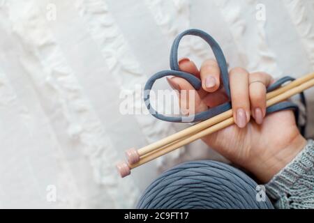 La main d'une femme tient un fil bleu tricoté, le pliant en forme de coeur. Concept d'amour pour le tricot et l'artisanat. Banque D'Images