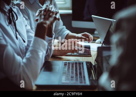 Divers employés de bureau utilisant des ordinateurs pendant les réunions d'affaires. Mains humaines. Gros plan. Concept d'équipe de brainstorming. Image teintée Banque D'Images