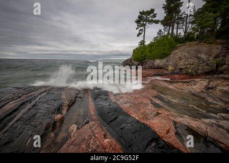 Des vagues grossièrement écrasont le substrat rocheux de la rive nord du lac supérieur. Banque D'Images