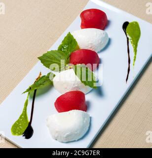 De belles boules de glace avec de la tomate sur la plaque blanche Banque D'Images