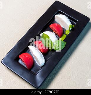 De belles boules de glace avec de la tomate sur l'assiette noire Banque D'Images
